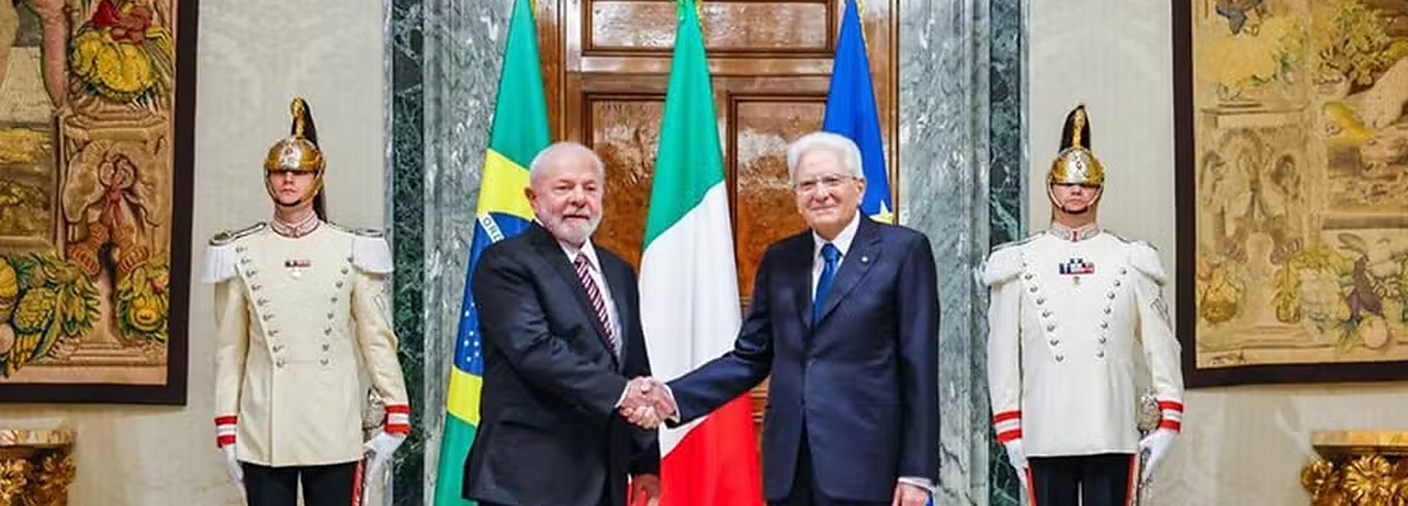 Os presidentes do Brasil e da Itália se cumprimentam diante das bandeiras dos dois países e da União Europeia